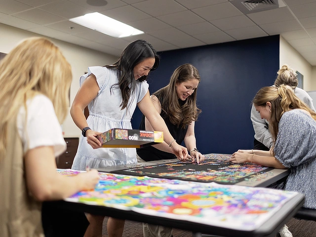 four female students working on a puzzle